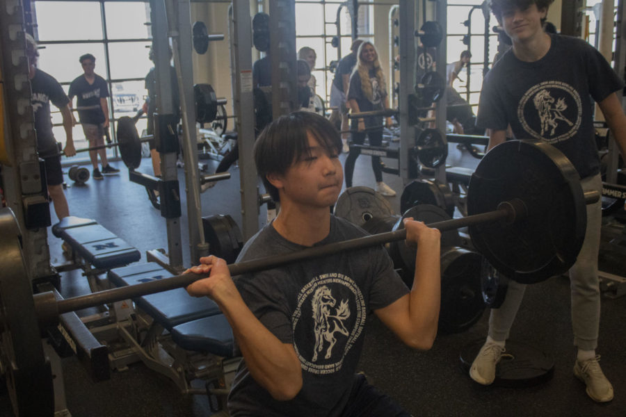 Adam Wang performing a power clean in weights alongside classmates.